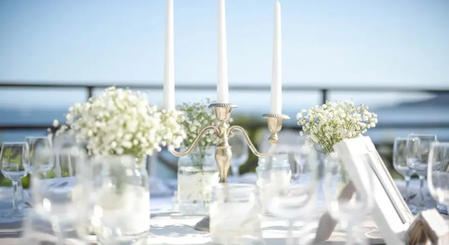 Décoration de mariage : bougies, fleurs et verres sur une table. La distance entre 2 tables mariage est suggérée par l'agencement.