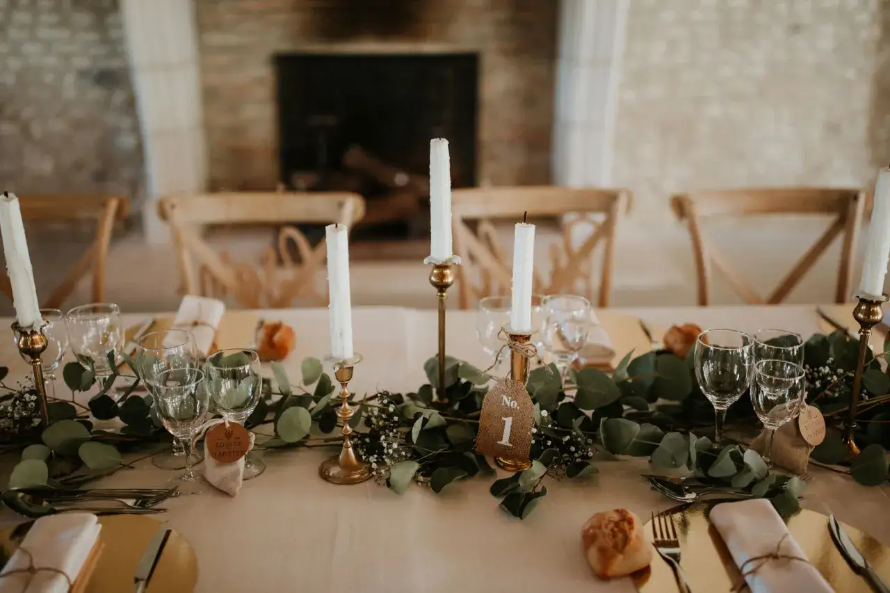 Décoration de table pour un mariage simple et original : bougies, verres, eucalyptus et petits pains.