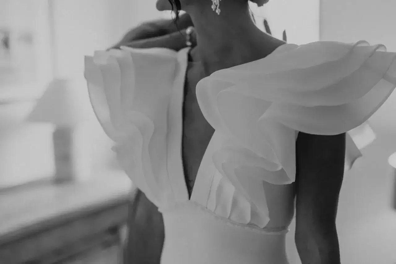 Détail d'une mariée portant une robe de mariage portugaise avec des volants spectaculaires sur les épaules.