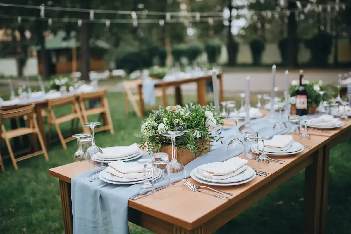Tables dressées en extérieur pour un mariage, avec des fleurs et des bougies. Idéal pour organiser son mariage soi-même avec goût.