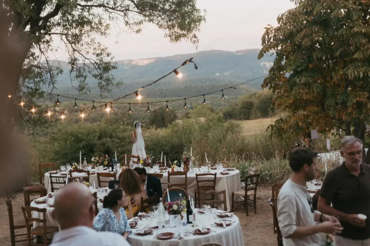 Un mariage sans musique en plein air, avec des tables dressées et des guirlandes lumineuses, sous un ciel crépusculaire.