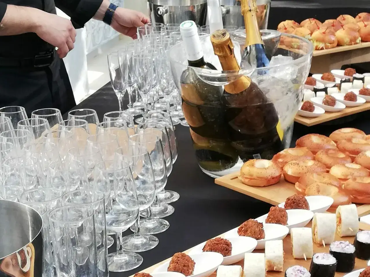 Bouteilles de champagne dans un seau à glace, verres à pied et petits fours prêts pour un événement. Le droit de bouchon traiteur est bien géré ici.