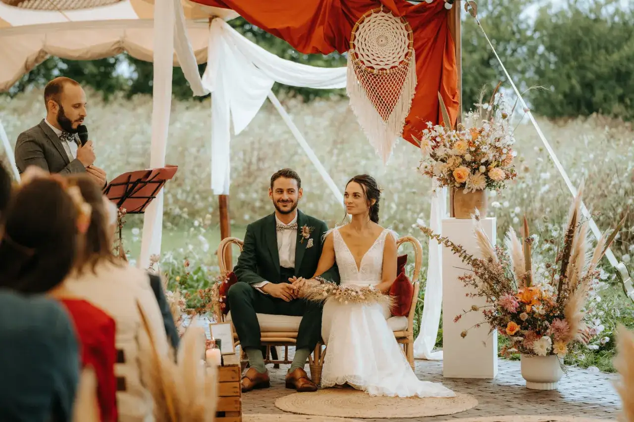 Cérémonie de mariage en plein air, le marié et la mariée assis, entourés de fleurs. Une célébration de tradition mariage : les 4 éléments.