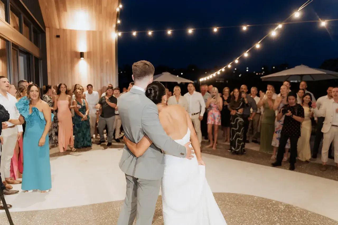 Le couple danse sous les guirlandes lumineuses, entouré de leurs invités. Une scène qui capture les plus belles surprises de mariage.