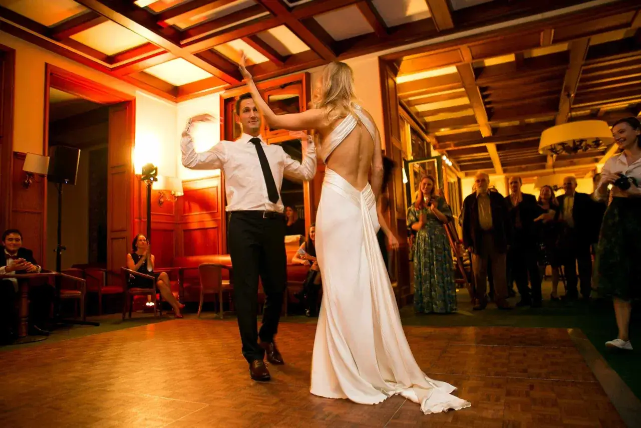 Un couple danse sur une chanson slow mariage français. La mariée porte une robe blanche, le marié un costume sombre.