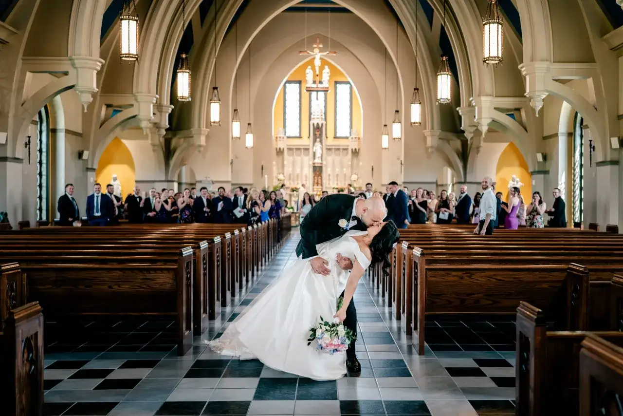 Un baiser passionné scelle l'entrée de l'église pour ce mariage émouvant. Les mariés, entourés de leurs invités, célèbrent leur amour.