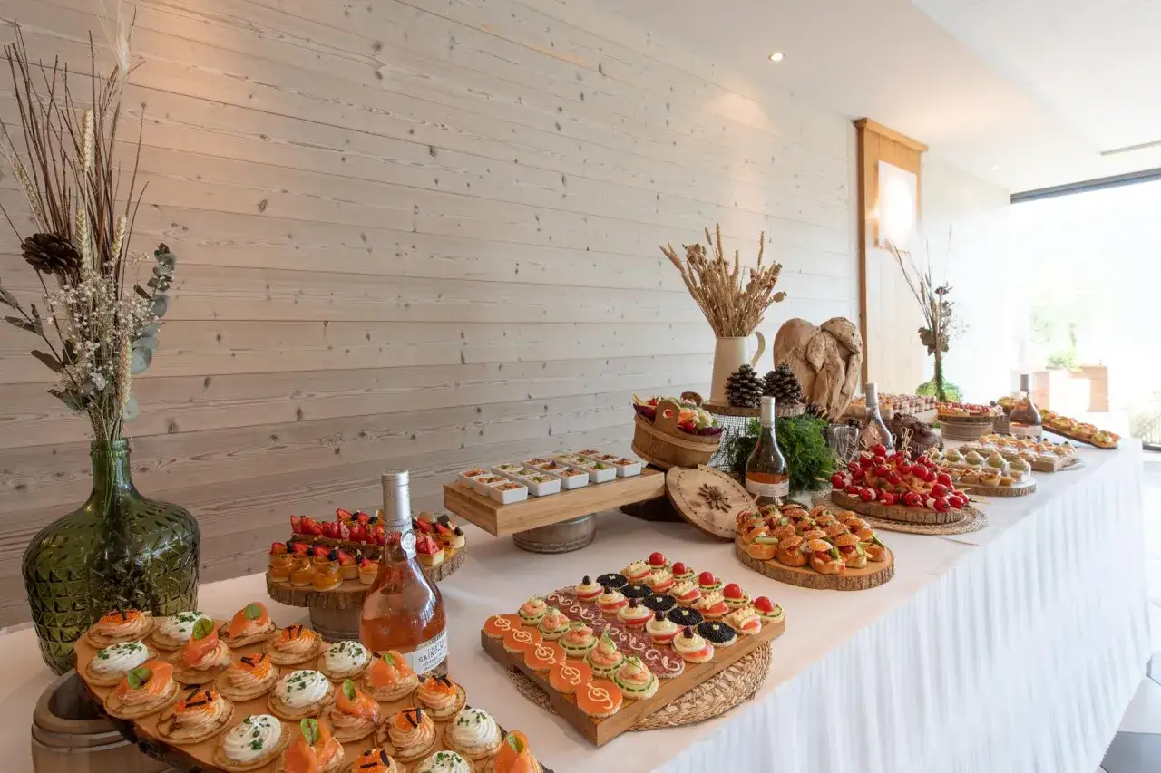 Buffet de brunch mariage avec mini-sandwichs, tartes aux fruits, brochettes et bouteilles de rosé.