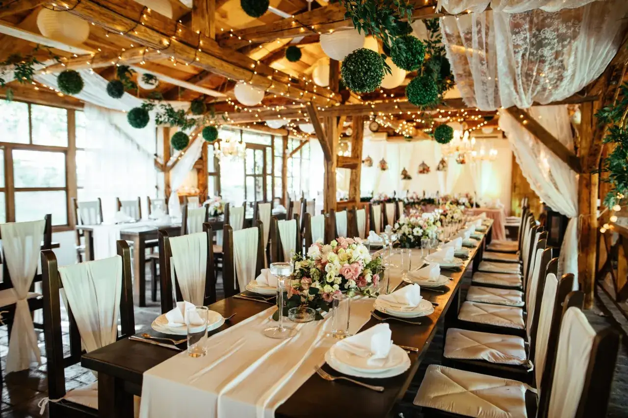 Une salle de réception rustique décorée pour un mariage. Tables dressées, fleurs, lumières douces. Idéal pour organiser son mariage soi-même.