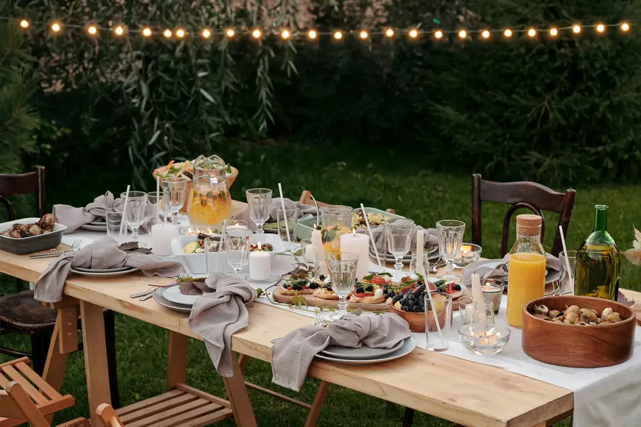 Table dressée pour un mariage en plein air, avec des lumières chaudes. Une belle idée brunch mariage avec des mets frais et des boissons fruitées.