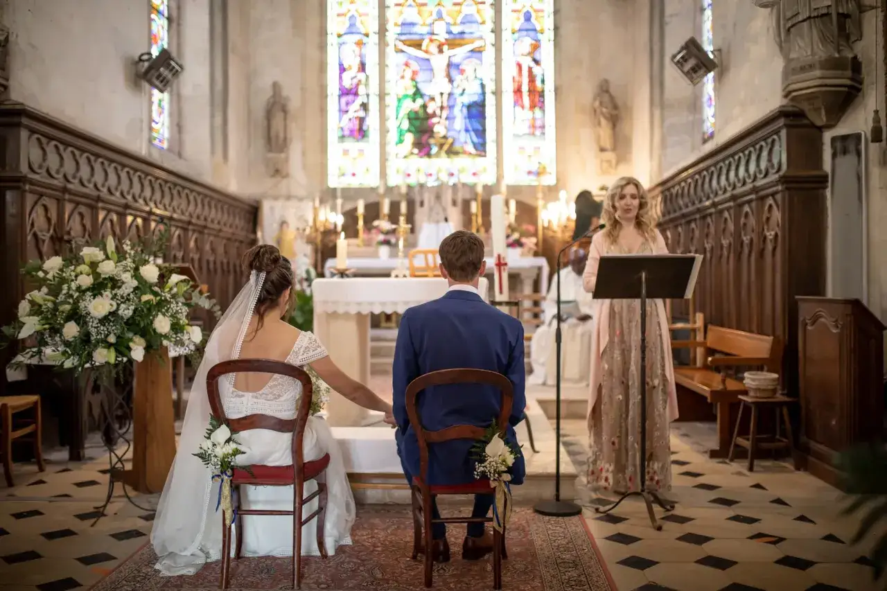 La mariée et le marié écoutent la musique de mariage à l'église. Une femme chante devant un pupitre.