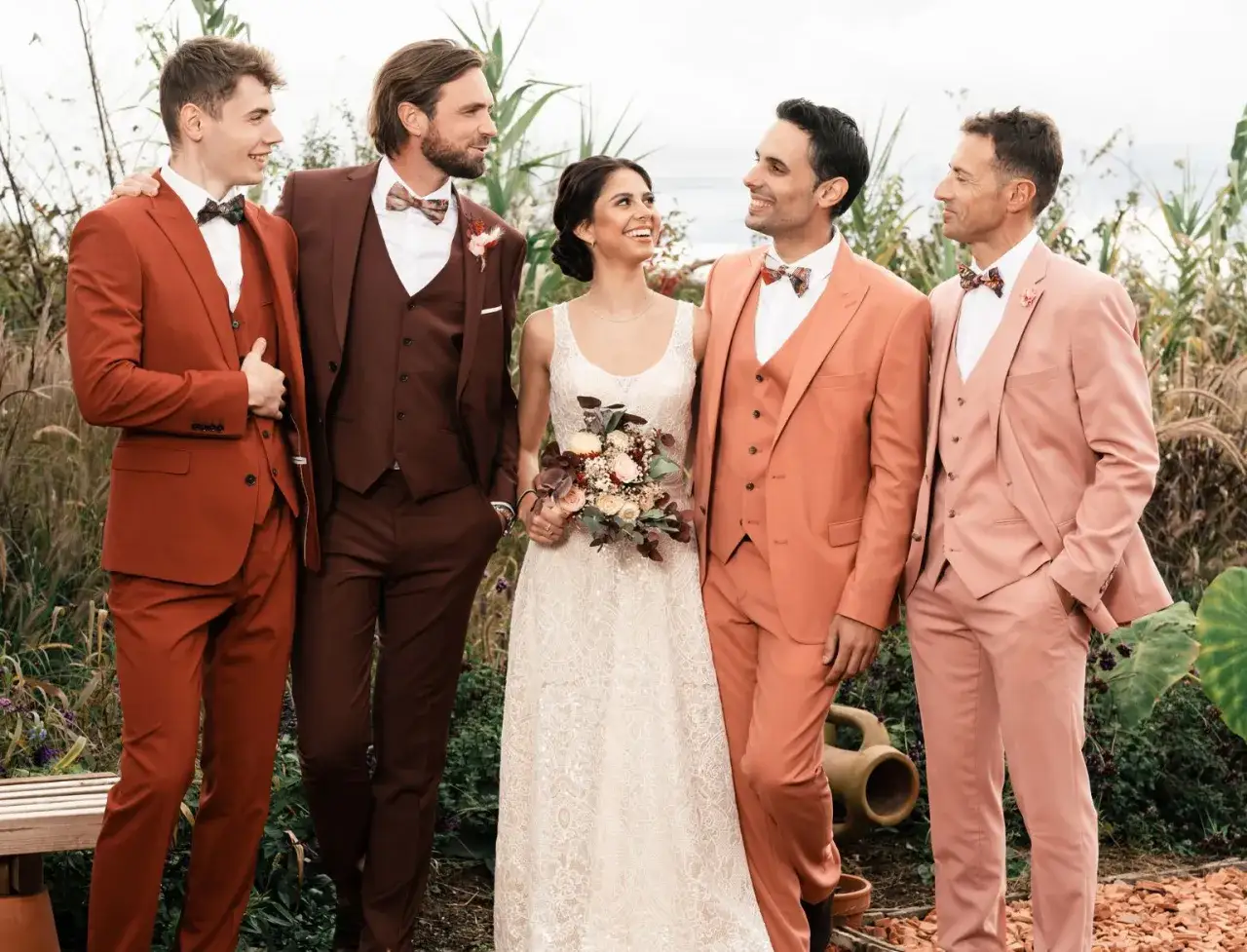 Mariés et témoins arborent des costumes de mariage aux couleurs audacieuses : rouille, bordeaux, corail et rose poudré.