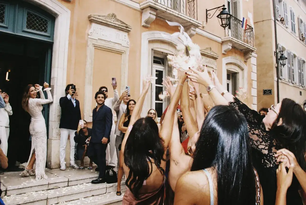 Des mains lancent des pétales et un bouquet, célébrant un tradition mariage francais devant l'Hôtel de Ville.
