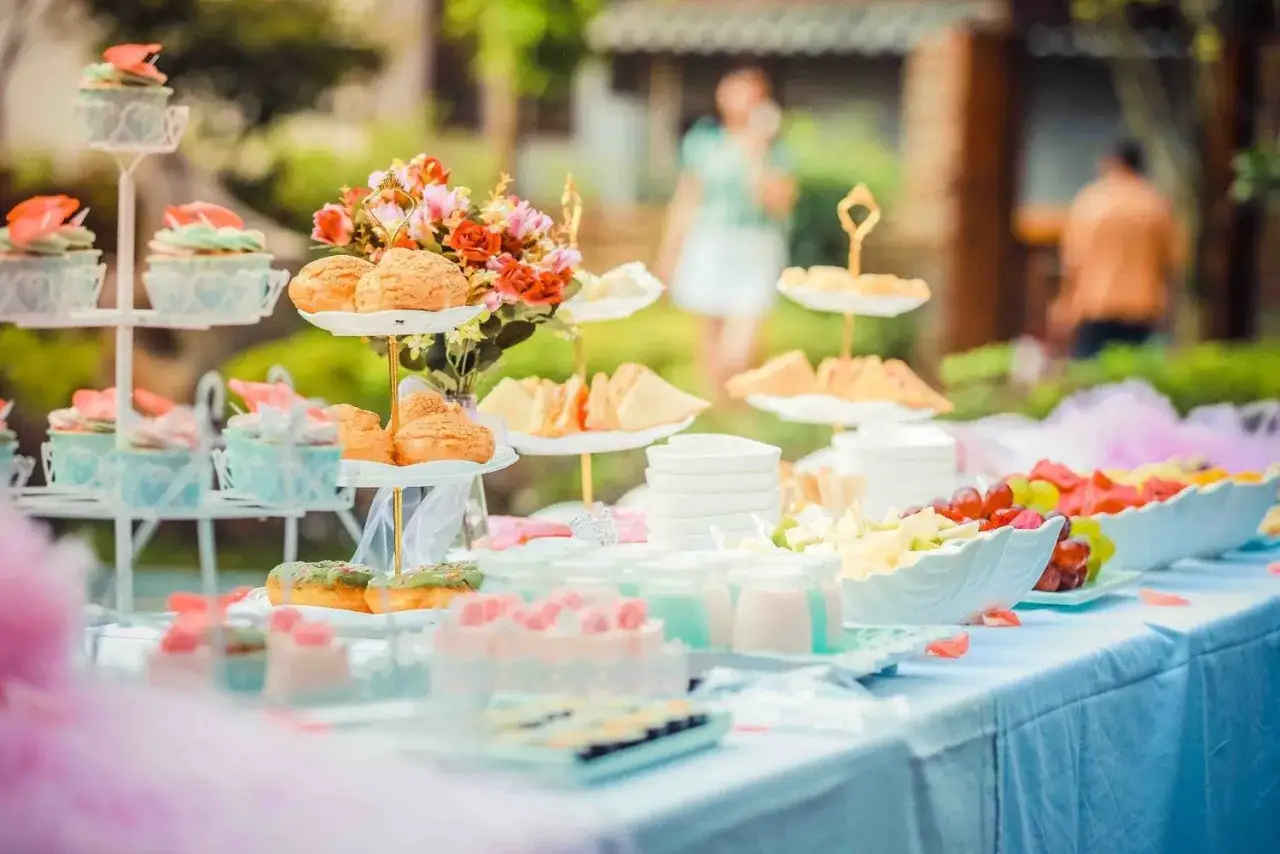 Buffet de mariage petit budget : cupcakes, choux, fruits frais et petits gâteaux joliment présentés en extérieur.