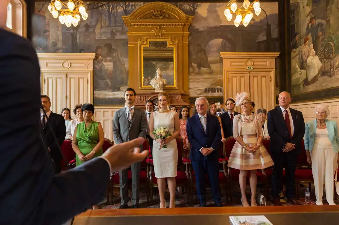 Le marié, son témoin et le garçon d'honneur se tiennent prêts pour la cérémonie. La mariée, radieuse, tient son bouquet.