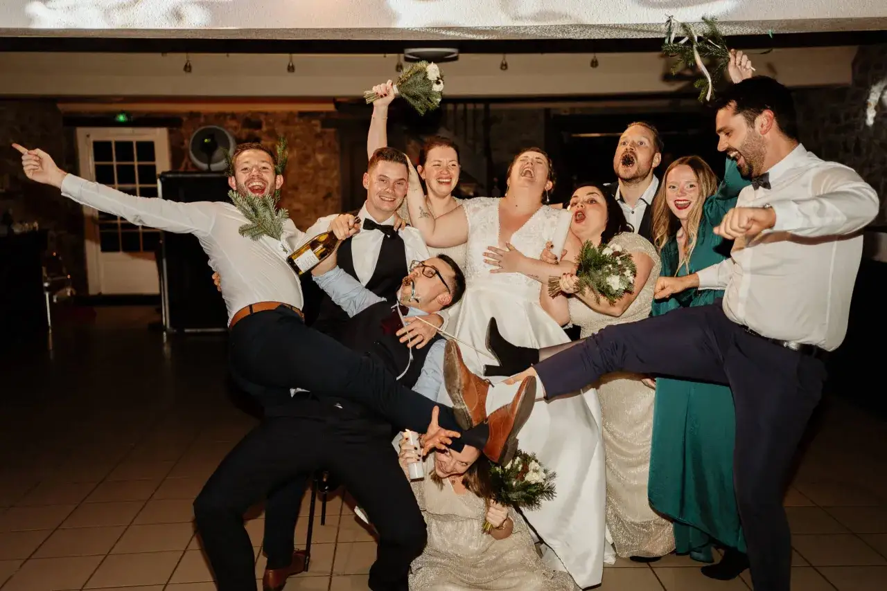Un groupe d'amis célèbre un mariage surprise émouvant, avec des rires, des bouteilles de champagne et des bougies.