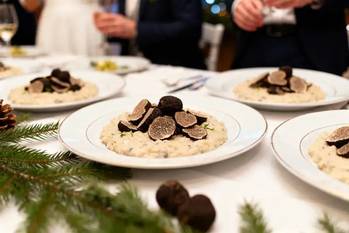 Un délicieux repas mariage hiver : risotto crémeux garni de truffes noires fraîches, servi sur des assiettes élégantes.