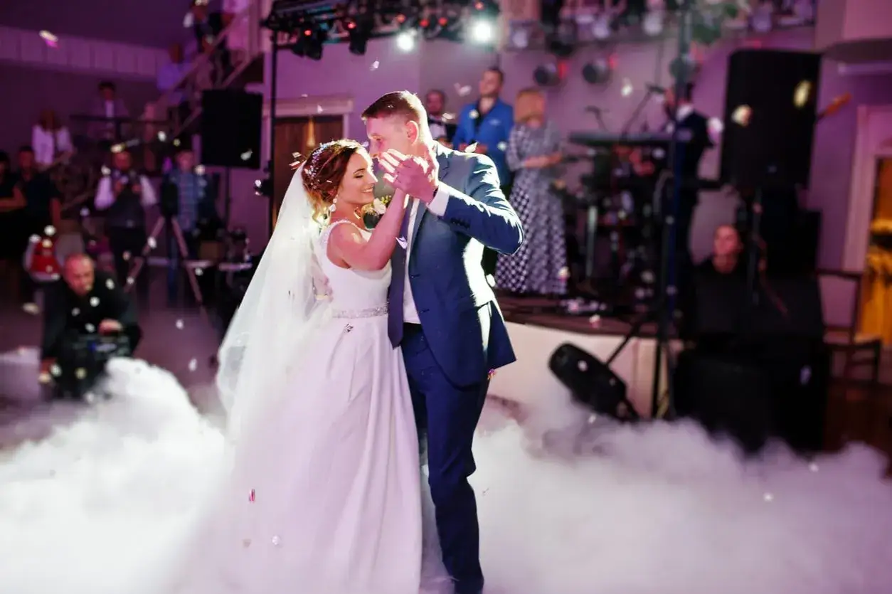 Un couple danse lors de l'ouverture de bal de leur mariage, entouré de fumée et de confettis.