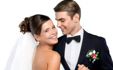 Un jeune couple marié, souriant et complice. La mariée, voile sur la tête, et le marié, nœud papillon, se préparent pour la fête. Combien donner à un mariage cousin ?