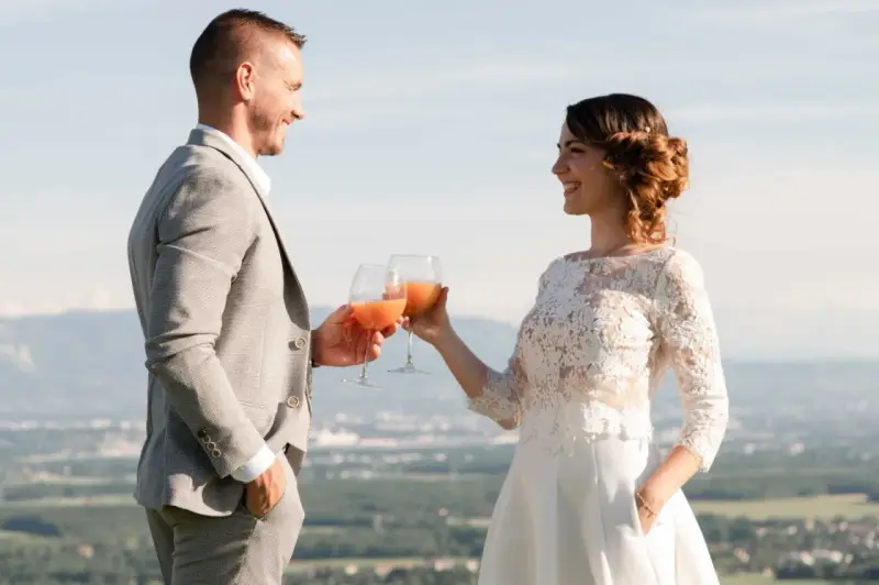 Un couple marié trinque avec des cocktails fruités, une belle quantité de soft pour un mariage en plein air.