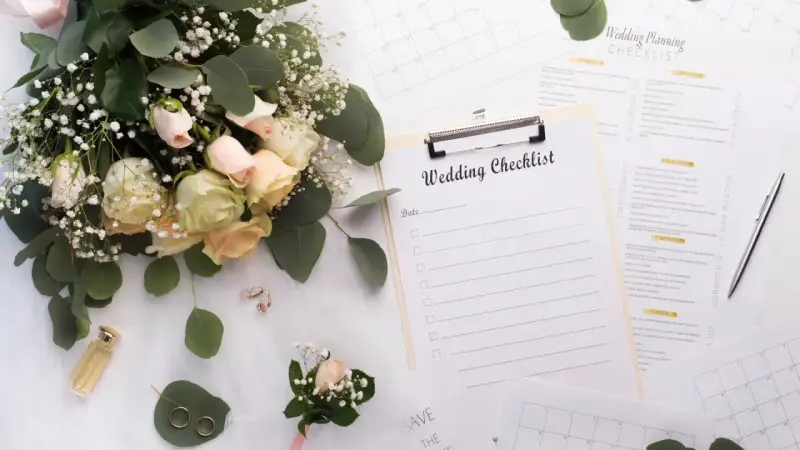 Un bouquet de roses, des alliances et une liste de mariage pour organiser son mariage soi-même.