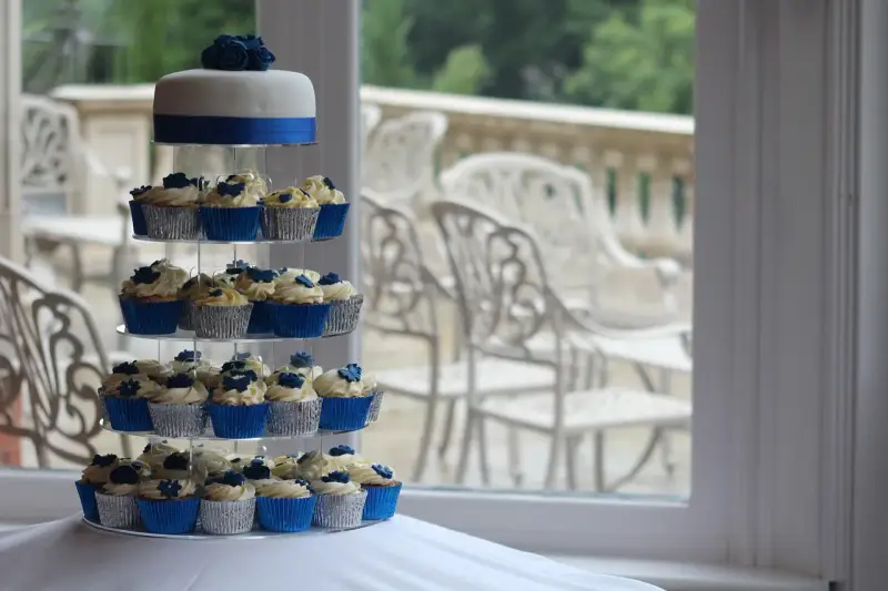 Magnifique pièce montée de cupcakes bleus et blancs, décorée de roses en sucre.