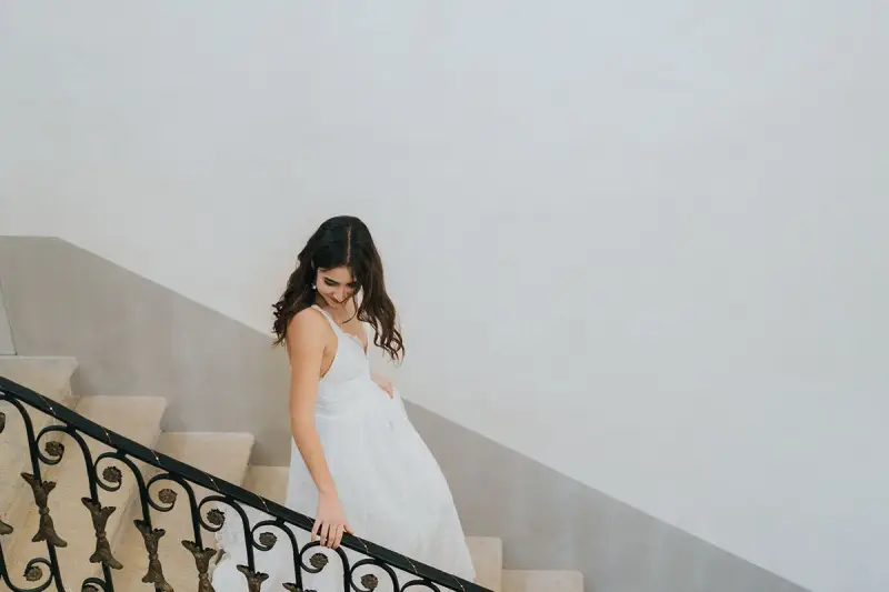 Une mariée descend un escalier, sa robe blanche fluide. Un moment clé pour comment choisir sa robe de mariée.